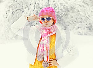 Fashion winter woman wearing a colorful knitted hat scarf having fun over snowy tree