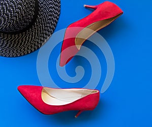 Fashion woman accessories set. Trendy fashion red shoes heels, stylish big hat. blue background.