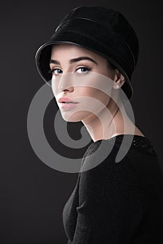 Fashion woman. Black and white portrait of beautiful young elegant lady in black dress and hat. Vintage styling. Beauty, fashion