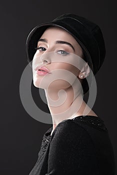 Fashion woman. Black and white portrait of beautiful young elegant lady in black dress and hat. Vintage styling. Beauty, fashion