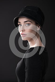 Fashion woman. Black and white portrait of beautiful young elegant lady in black dress and hat. Vintage styling. Beauty, fashion,