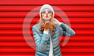 Fashion woman blowing red lips sends an air kiss on background