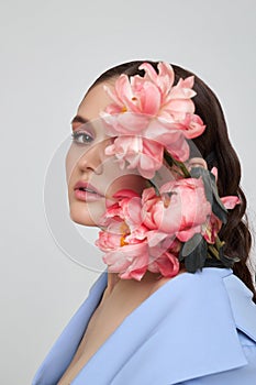 Fashion woman in blue suit with pink flowers, beauty face portrait. Art studio portrait of a young woman on a white background,