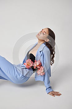 Fashion woman in blue suit with pink flowers, beauty face portrait. Art studio portrait of a young woman on a white background,