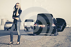 Fashion woman calling on cell phone next to broken car