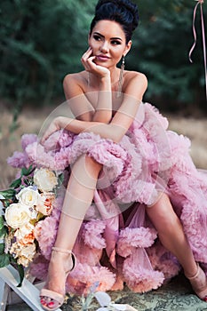 Fashion woman dressed in pink stunning dress surrounded of French Macarons