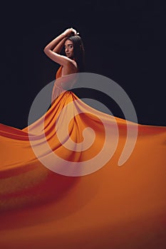 Fashion, woman and elegant with beauty on dark background, portrait and model in orange dress in studio. Indian female