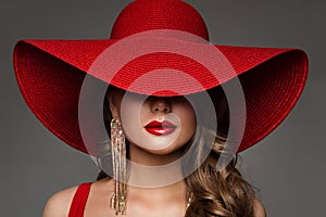 Fashion Woman in Hat with Red Lips Make up and Golden Earring. Beauty Model Face Hidden by Wide Broad Brim Hat. Elegant Lady