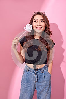 Fashion woman having fun with lollipop over pink background