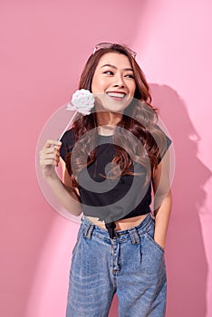 Fashion woman having fun with lollipop over pink background