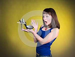 Fashion woman looking at high-heel shoe. Women love shoes concept. Screaming girl and high heels shoes on yellow background.