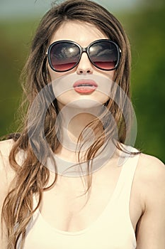 Fashion woman model posing. woman in summer sunglasses with long curly brunette hair