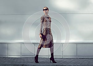 Fashion woman model wearing a leopard dress is walking