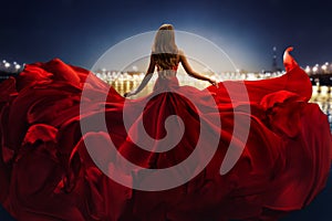 Fashion Woman in Red fluttering Dress Back Side Rear View. Glamour Model dancing with Long Silk Fabric flying on Wind over Night