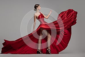 Fashion woman in red long dress. Gray background