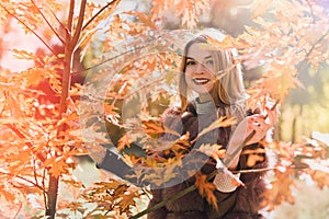 Fashion woman. Smiling girl in fur coat posin in autumn park with trees and ivy