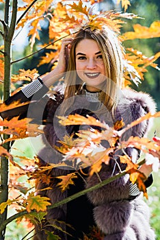 Fashion woman. Smiling girl in fur coat posin in autumn park with trees and ivy