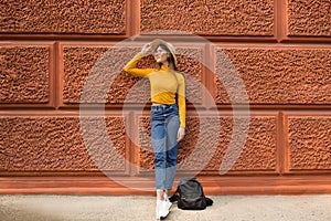 Fashion woman is standing near the orange wall.