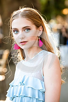 Fashion woman with stylish makeup and long blonde hair. Pretty girl with fashionable hair and pink earring. summer