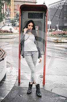 Fashion woman talking in the retro phone booth