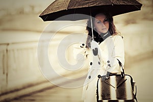 Fashion woman with umbrella walking in rain on city street