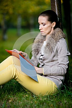 Fashion woman using a tablet computer outside in evening park