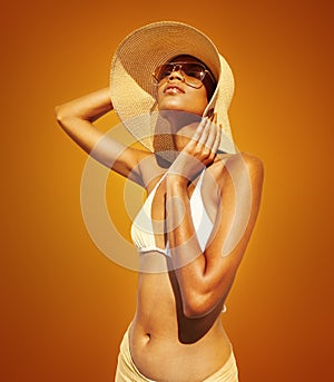 Fashion woman wear sunglasses, sun straw hat, bikini and pareo. African latin american woman  on orange background,