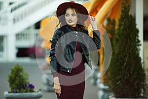 Fashion woman is wearing warm fashion autumn clothes and hat infront walking in the city center, urban style