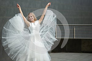 Fashion woman in white long dress in the city. Standing against the wall