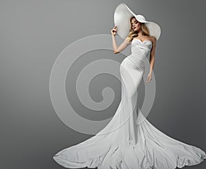 Fashion Woman in White Wedding Dress over Gray Background. Elegant Bride in Mermaid Gown and White Summer Hat. Beautiful Sexy Girl