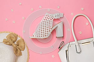 Fashion women`s accessories and shoes on pink background with flowers. Flat lay.