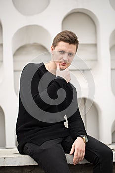 Fashion young man in black clothes on white wall background