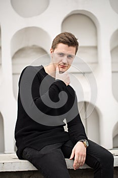 Fashion young man in black clothes on white wall background.