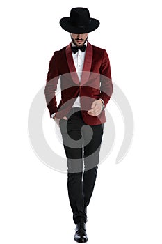 Fashion young man in red velvet tuxedo walking and looking down photo