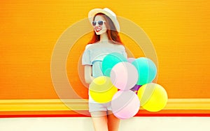 Fashion young woman with an air colorful balloons on a orange
