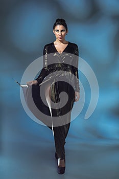 Fashion young woman in black stilish dress. Glamour model in fashion pose, stylish make-up, fashion heels.