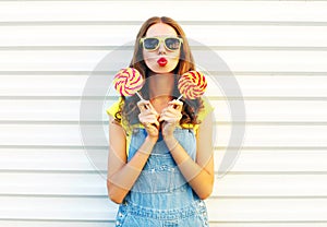 Fashion young woman holding a lollipops and blowing her lips