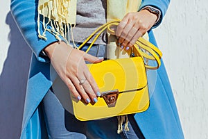 Fashion. Young woman holding stylish handbag and wearing trendy blue coat. Spring female clothes and accessories