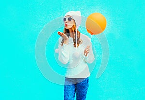 Fashion young woman sends an air kiss holds balloon in white hat