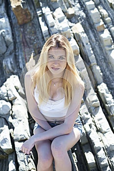 Fashion young woman sitting on sea rocks.