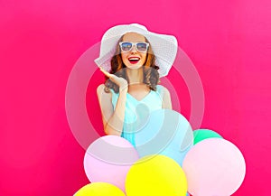 Fashion young woman is surprised with an air colorful balloons is having fun on pink background