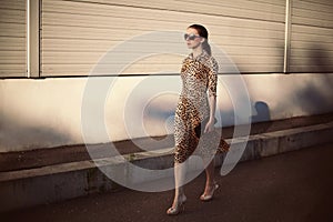 Fashion young woman wearing a leopard dress and handbag clutch