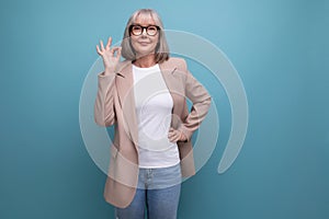 fashionable 60s middle aged business woman in stylish look approves on a bright studio background