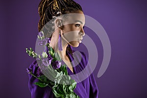 Fashionable african american girl posing with purple eustoma flowers,