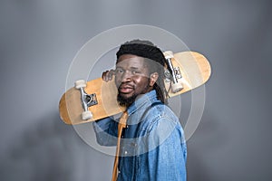 fashionable african american man with skate on shoulder