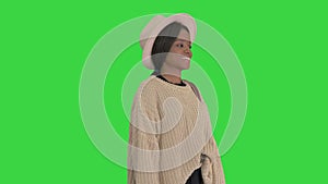 Fashionable african american woman posing in knitwear and white hat on a Green Screen, Chroma Key.