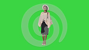 Fashionable african american woman posing in knitwear and white hat on a Green Screen, Chroma Key.