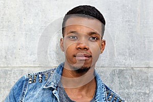 Fashionable attractive african man standing by wall staring