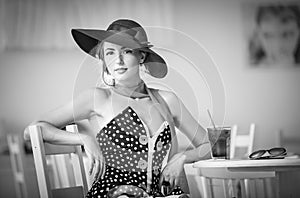 Fashionable attractive lady with hat and scarf sitting in restaurant