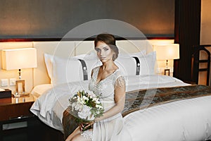 Fashionable and beautiful brunette model girl with stylish wedding hairstyle and with bright makeup in white peignoir